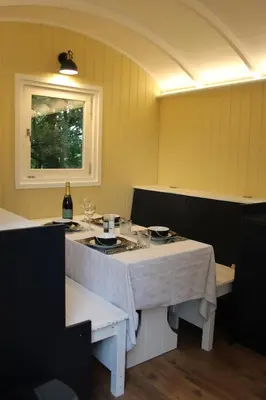 a dining room with a table and a bottle of wine at The Tawny Shepherd Hut, Whitehouse Farm in Stowmarket