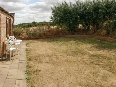a yard with a table and chairs and a tree at Haycart Barn in Norwich