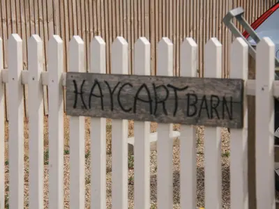 a sign on a white fence with the wordmary bark at Haycart Barn in Norwich