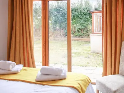 a bedroom with a bed and a large window at Haycart Barn in Norwich
