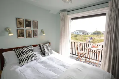 a bedroom with a bed and a balcony with a view at 2 The Dunes, Thorpeness in Thorpeness