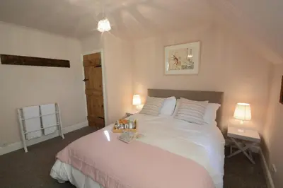 a bedroom with a large white bed with two lamps at 2 The Dunes, Thorpeness in Thorpeness