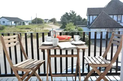 a table and two chairs on a balcony at 2 The Dunes, Thorpeness in Thorpeness