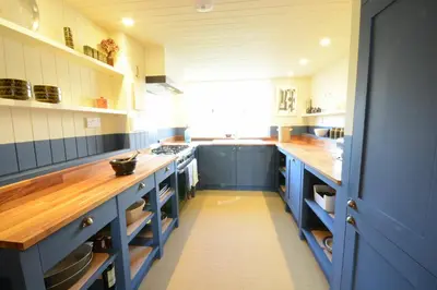 a large kitchen with blue cabinets and blue counters at 2 The Dunes, Thorpeness in Thorpeness