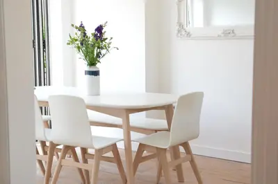 a white dining room table and chairs with a vase of flowers at 4 The Dunes, Thorpeness in Thorpeness
