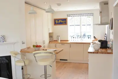 a kitchen with white cabinets and a counter with stools at 4 The Dunes, Thorpeness in Thorpeness