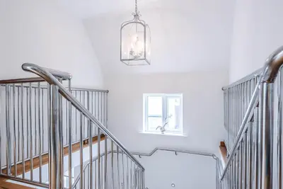 a staircase with a chandelier and white walls at Guild House, Aldeburgh in Aldeburgh