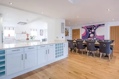 a kitchen with white cabinets and a bar with black chairs at Guild House, Aldeburgh in Aldeburgh