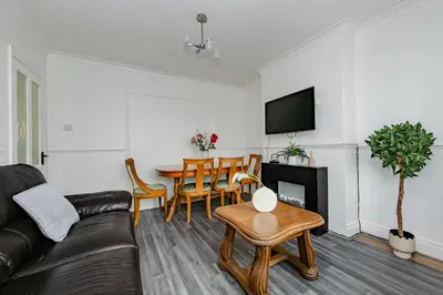 a living room with a black leather couch and a table at The Comfy Contractors Resort, Free Private Parking & Wifi, 7 beds in Colchester