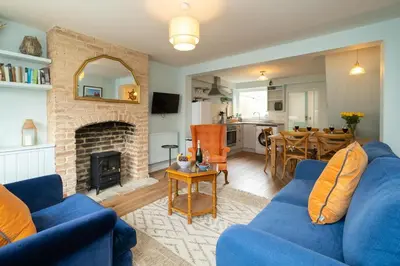 a living room with a blue couch and a fireplace at Quay Cottage - Aldeburgh Coastal Cottages in Aldeburgh