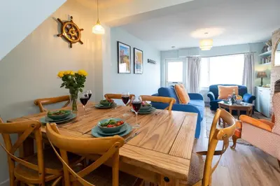 a dining room and living room with a wooden table at Quay Cottage - Aldeburgh Coastal Cottages in Aldeburgh