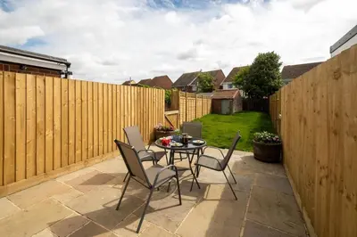 a patio with a table and chairs and a fence at Quay Cottage - Aldeburgh Coastal Cottages in Aldeburgh