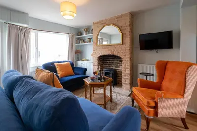 a living room with a blue couch and a fireplace at Quay Cottage - Aldeburgh Coastal Cottages in Aldeburgh