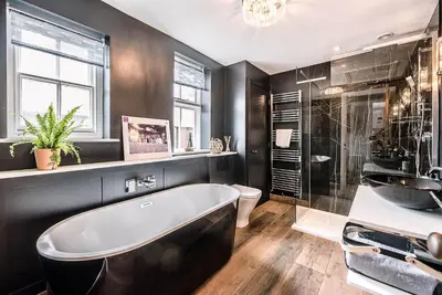 a black bathroom with a tub and a shower at The Picture House, Aldeburgh in Aldeburgh