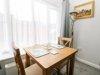 a wooden table with two chairs and a window at Jimmys Place in Diss