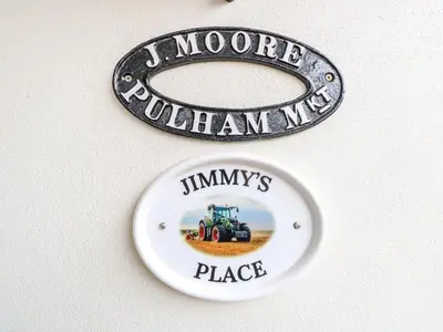 two signs on a wall with a tractor in a field at Jimmys Place in Diss