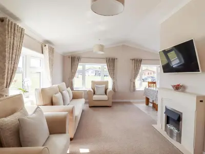 a living room with white furniture and a fireplace at 12 Bucklesham Park in Ipswich