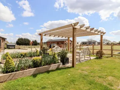 a wooden pergola in a garden with plants at 12 Bucklesham Park in Ipswich
