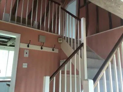 a staircase in a room with orange walls at Thatched Cottage in Wix