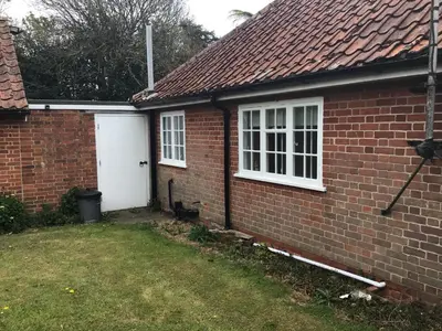 a brick house with a white door and a yard at Thatched Cottage in Wix