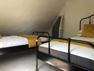 two twin beds in a room with a staircase at Thatched Cottage in Wix