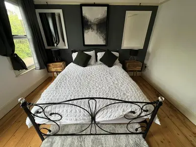 a bedroom with a black and white bed and two windows at Charming 3 bedroom property in Bury St Edmunds in Bury Saint Edmunds
