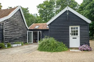 a black house with a white door at The Cart Lodge - Aldeburgh Coastal Cottages in Wickham Market