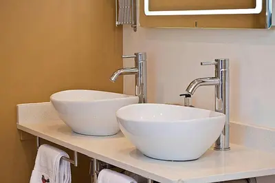 two sinks in a bathroom with two faucets at The Pheasantry in Wymondham