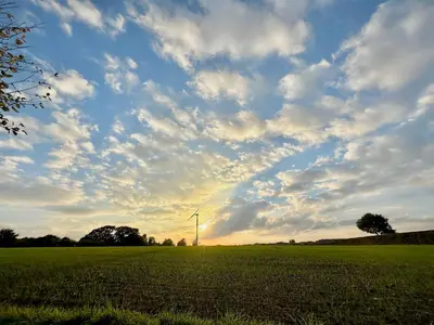 a windmill in a field under a cloudy sky at The Pheasantry in Wymondham