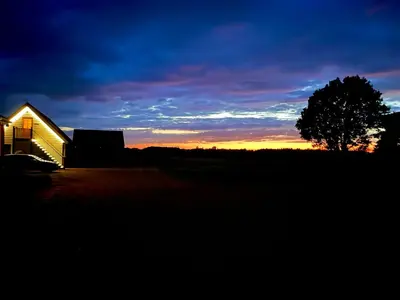 a house with a tree in front of a sunset at The Pheasantry in Wymondham