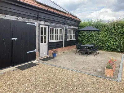 a patio with a table and an umbrella at The Shed in Long Stratton