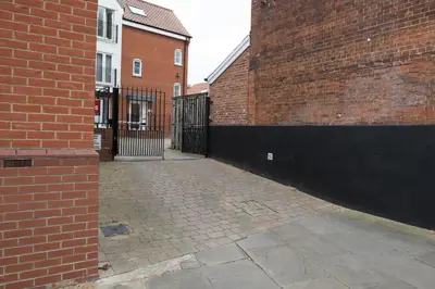 an empty alley with a brick building and a gate at Toothbrush Apartments - Central Ipswich - Gipping Mews in Ipswich