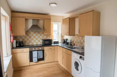 a kitchen with wooden cabinets and a white refrigerator at Toothbrush Apartments - Central Ipswich - Gipping Mews in Ipswich