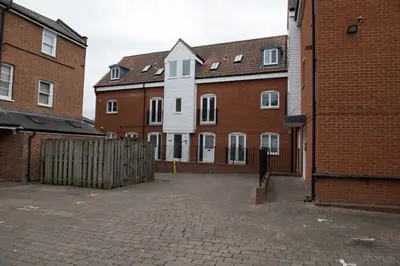 a group of brick buildings with a gate and a fence at Toothbrush Apartments - Central Ipswich - Gipping Mews in Ipswich