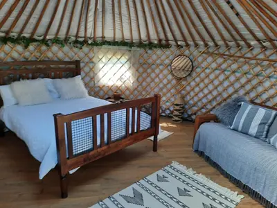 a bedroom with a bed and a couch in a yurt at Cranfield Retreat & Glamping in Long Melford