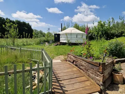 a wooden walkway in a garden with a yurt at Cranfield Retreat & Glamping in Long Melford