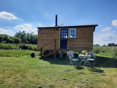 a tiny house in a field with a table and chairs at Cranfield Retreat & Glamping in Long Melford