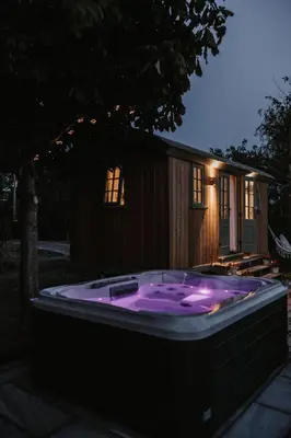 a large purple hot tub in front of a house at The Dragonfly Shepherds Hut in Colchester