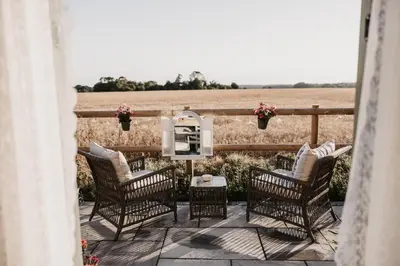 a patio with chairs and a table in front of a field at The Dragonfly Shepherds Hut in Colchester