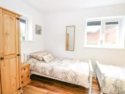 a bedroom with two beds and a dresser and two windows at Walnut Shade in Attleborough