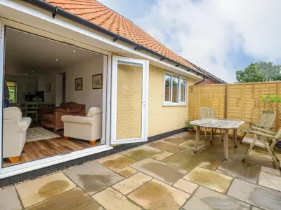 a patio with sliding glass doors and a table at Walnut Shade in Attleborough