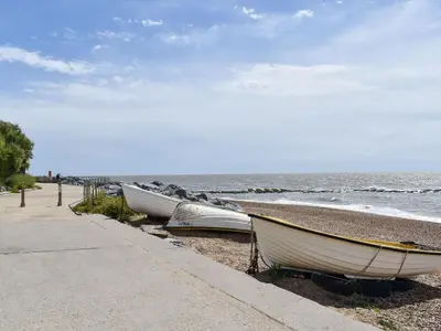 a row of boats on the shore of a beach at Beach View Cottage in Felixstowe
