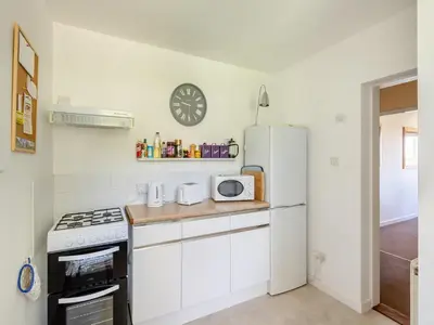 a kitchen with a white refrigerator and a clock on the wall at Beach View Cottage in Felixstowe