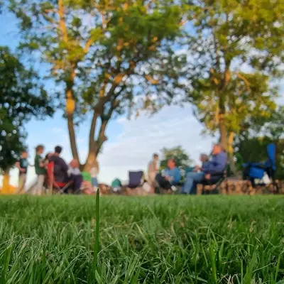 a group of people sitting in chairs in a park at Willow Grove Farm Glamping in Lakenheath
