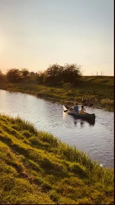 two people are in a boat on a river at Willow Grove Farm Glamping in Lakenheath