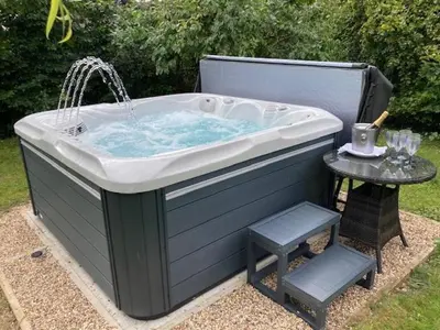 a large bath tub with a table and a stool at The Suites at Pannells Ash in Castle Hedingham