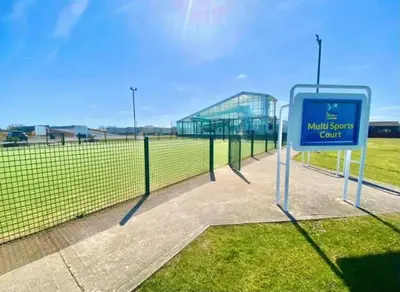 a sign in front of a tennis court with a fence at Lodge Sleeps 8- Parking Wifi Campsite Amenities in Jaywick Sands