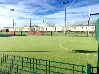 a tennis court with a net on a field at Lodge Sleeps 8- Parking Wifi Campsite Amenities in Jaywick Sands
