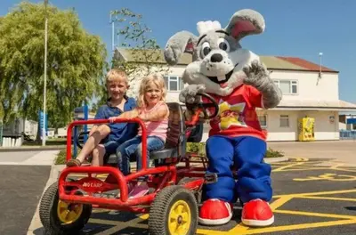 a boy and a girl riding in a toy pulled by a mascot at Lodge Sleeps 8- Parking Wifi Campsite Amenities in Jaywick Sands