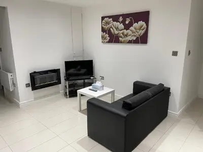 a living room with a black couch and a tv at Lovely holiday home in Southminster in Southminster